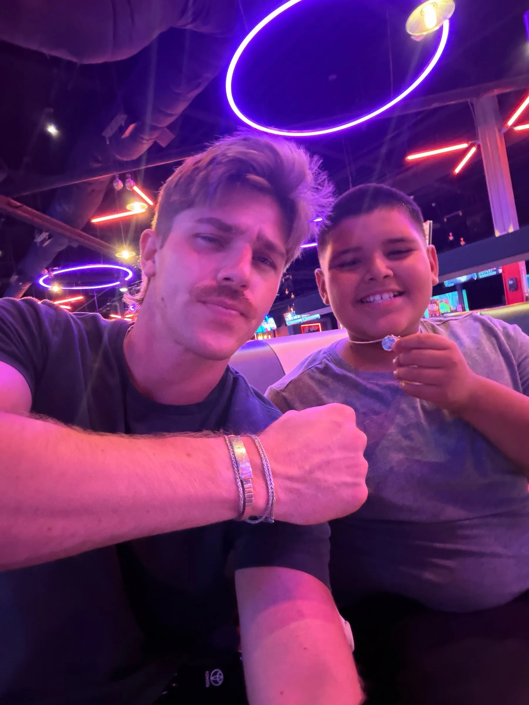 A mentor and his mentee taking a selfie at a neon arcade