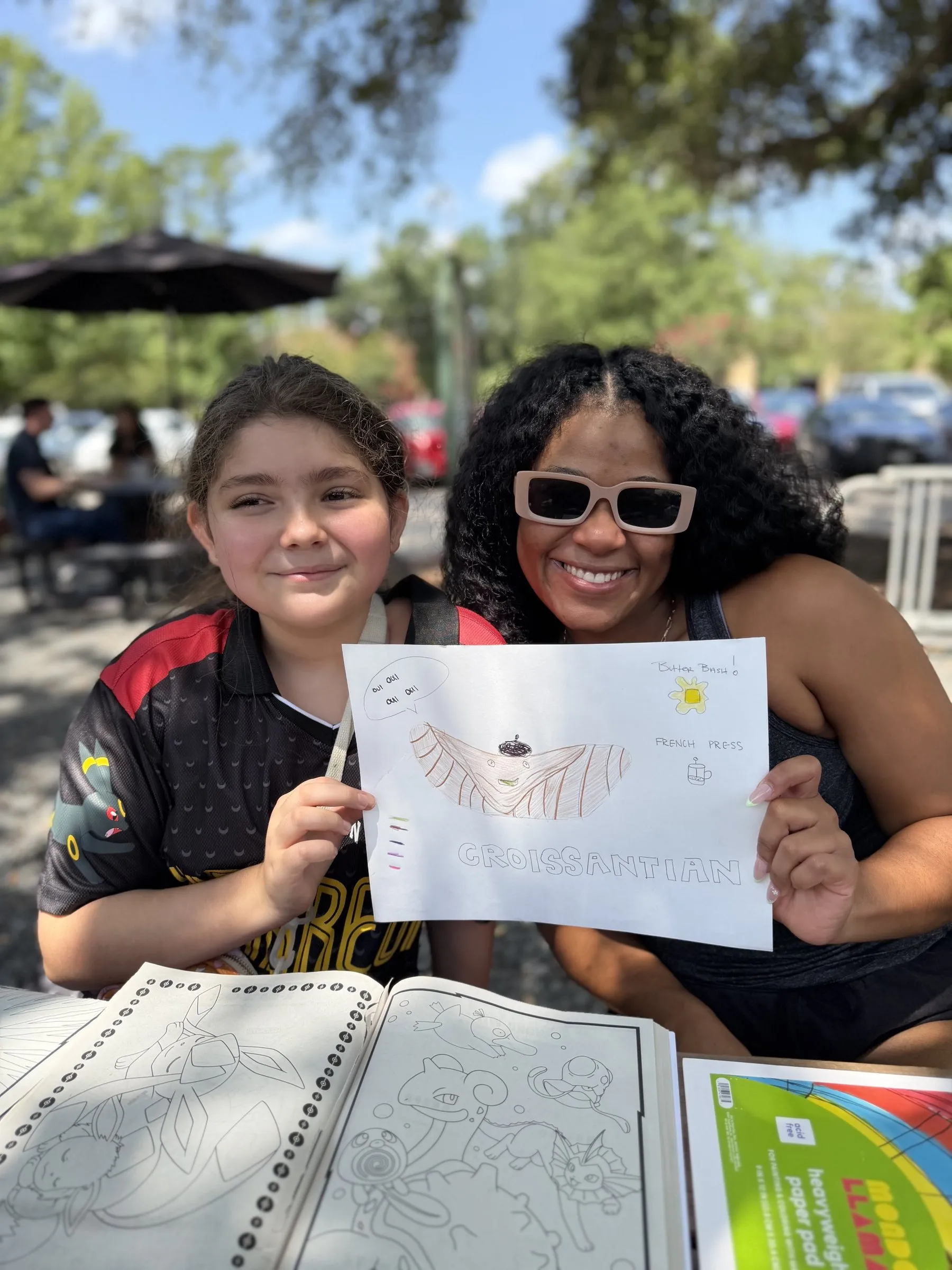 A mentee and her mentor holding up a drawing she made