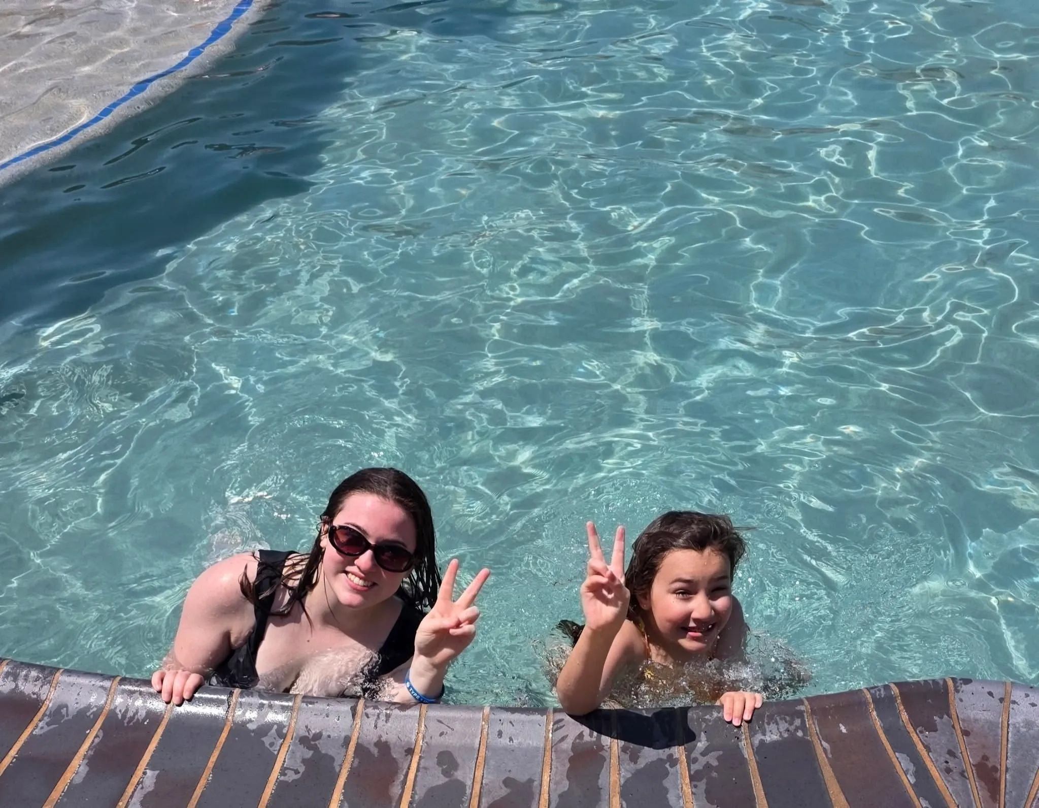 A braveONE mentor and mentee throwing peace signs in the pool