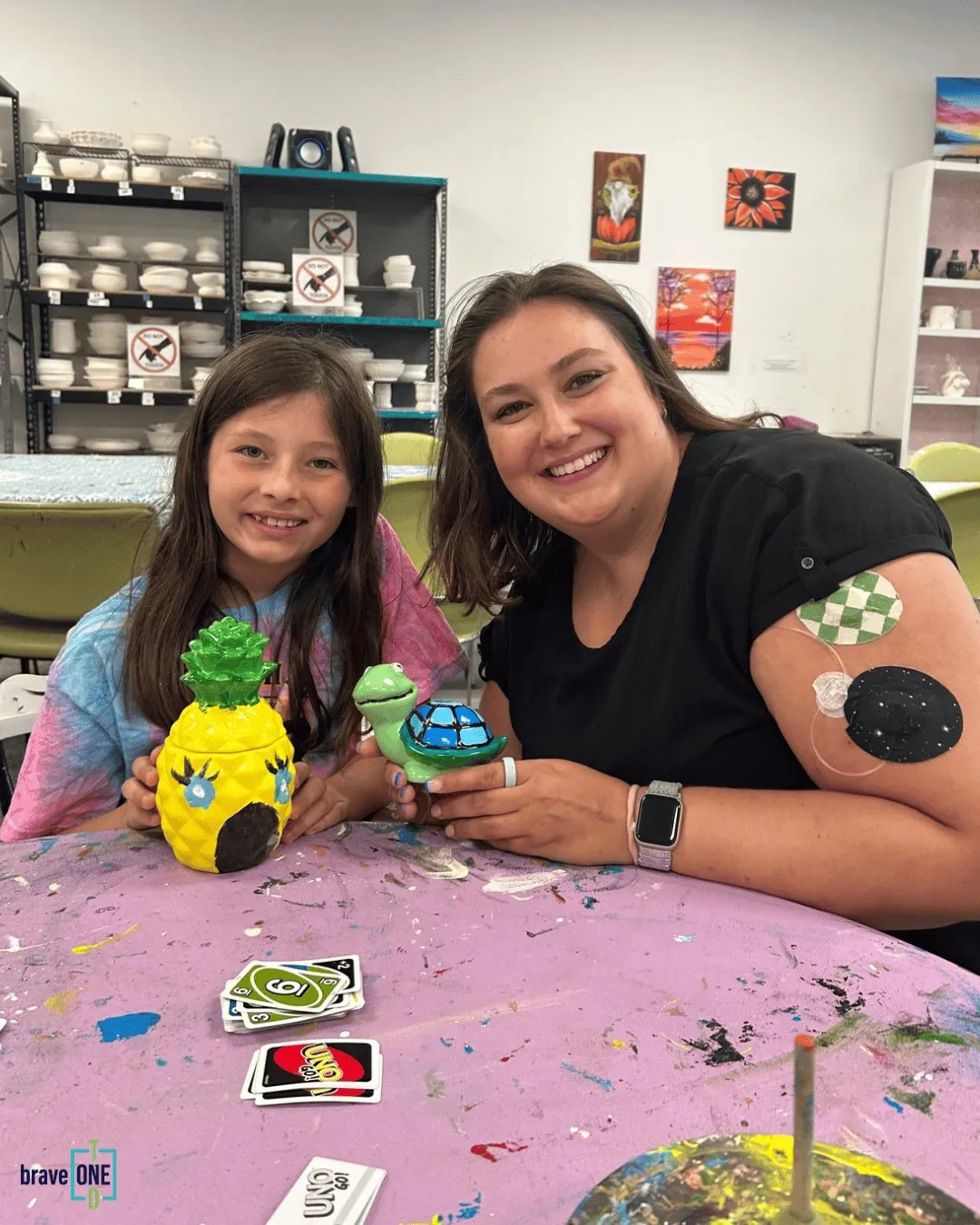A mentee and her mentor showing off the pottery they painted together
