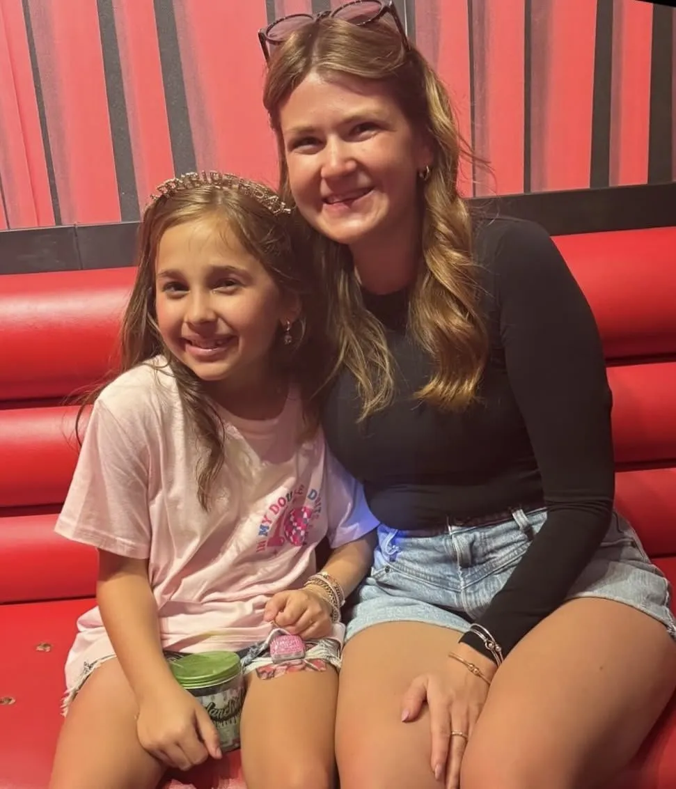 A mentee and her mentor smiling together in a restaurant booth